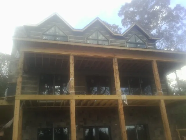 Dormers and porch framing on a large log home under construction — Roof Coating work by our crew in West Yellowstone