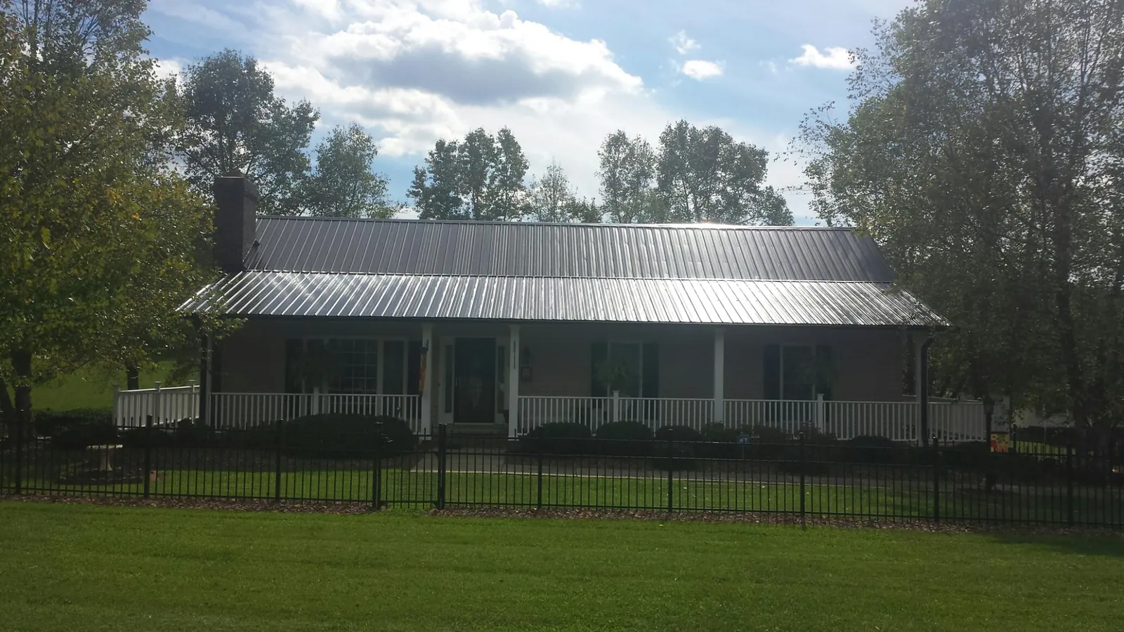 Gray metal roof on a brick ranch with a full width front porch — Gutter Guard Installation work by our crew in West Yellowstone