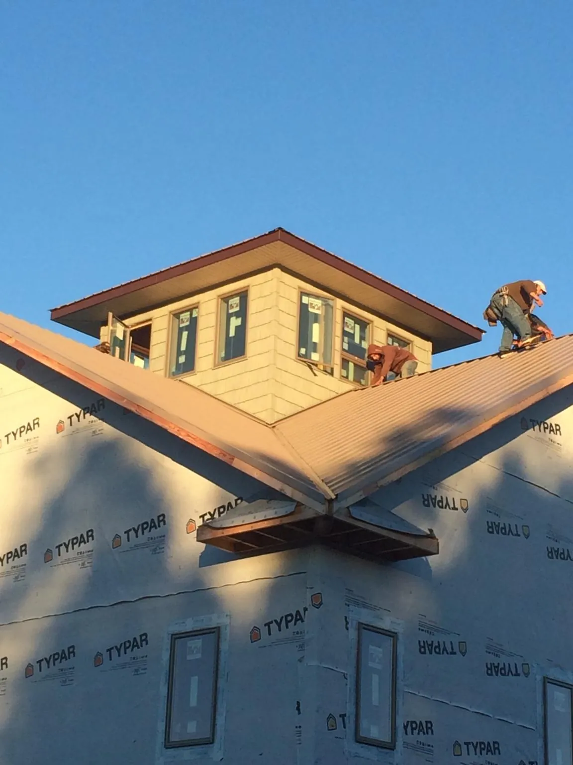 Roofers working around a rooftop cupola on a new metal roof at sunset — Roof Waterproofing in West Yellowstone by Roofing Brothers